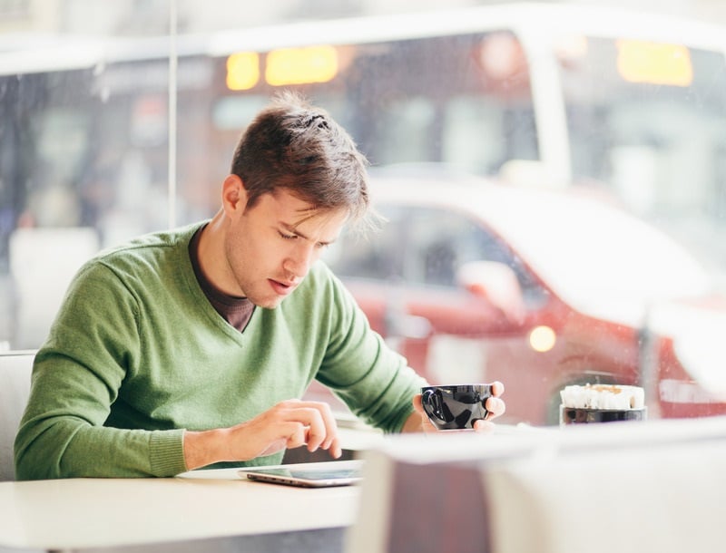 Mann sitzt im Café und informiert sich im Internet